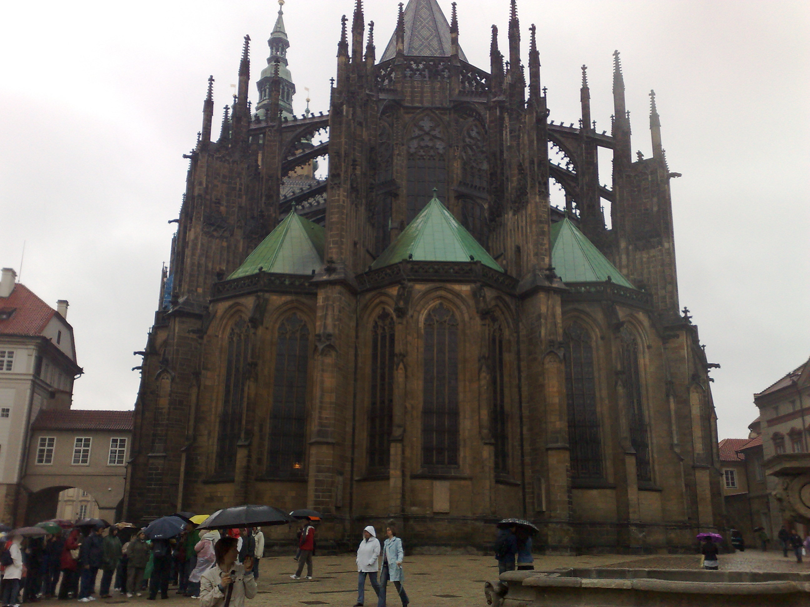 Gotische Kathedralenfassade in Prag mit Besuchern und Schirmen
